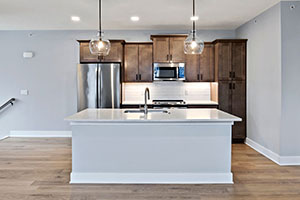 Interior photo of the Cambridge Townhome's kitchen island. Showing contemporary wood cabinetry and a stunning quartz counter top island